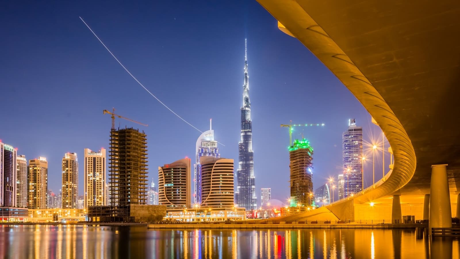 الخليج التجاري وبرج خليفة مضاءان ليلاً، من تحت أحد الجسور
